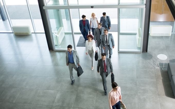 A group of professionally dressed employees entering office building