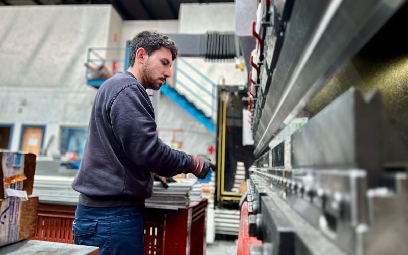 Aerospace metalworker operating bending machine in factory