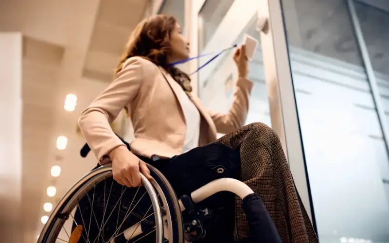 Close up of businesswoman in wheelchair using ID card to enter in the office