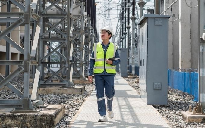 Electrical engineer walking and inspecting high voltage equipment at power substation, monitoring for industrial safety