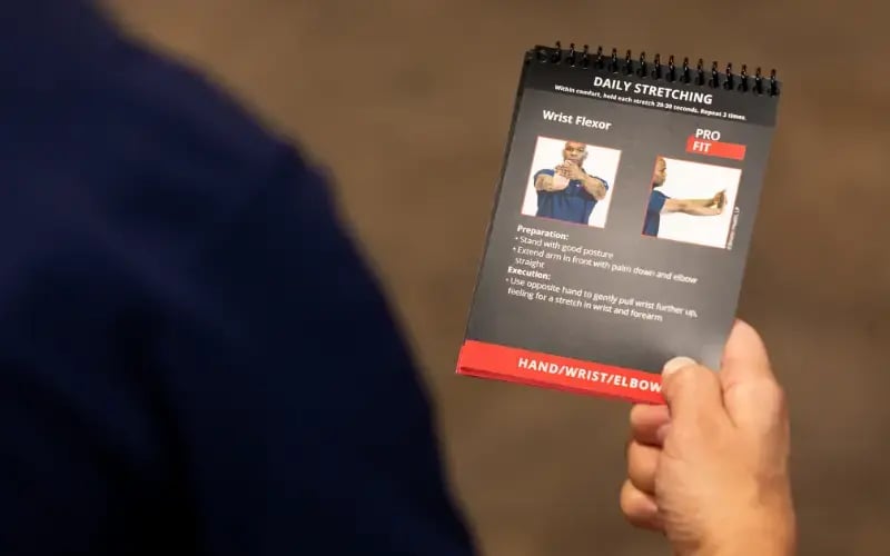 Employee holding a Briotix Health PRO Fit Daily Stretching Guide