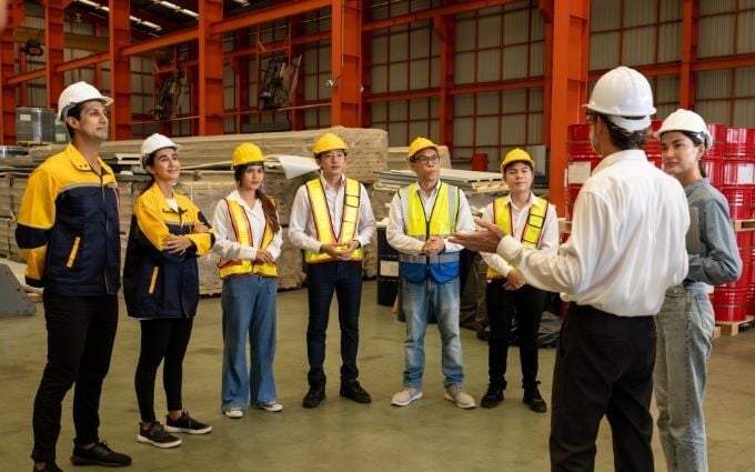 Factory workers gather for a team safety meeting