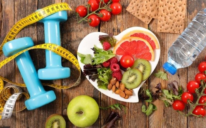 Group of healthy lifestyle images including weights, water, and a plate of fruits and vegetables