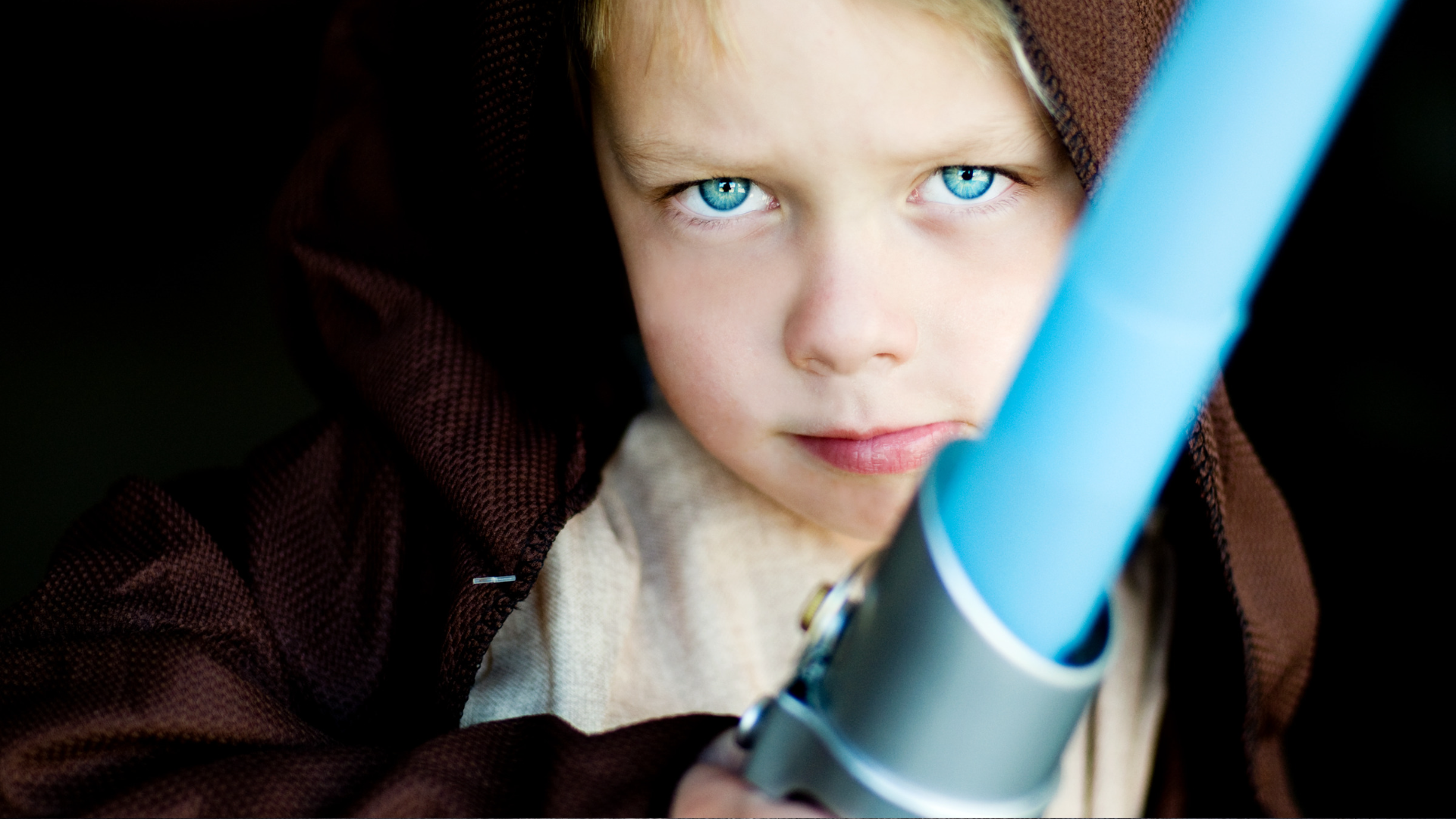 a kid wearing a Jedi costume and holding a lightsaber