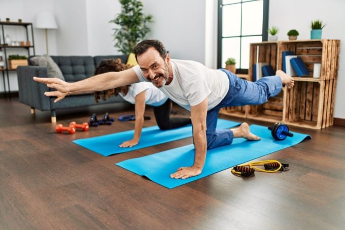 Man doing stretching excersises at home on yoga mat - small