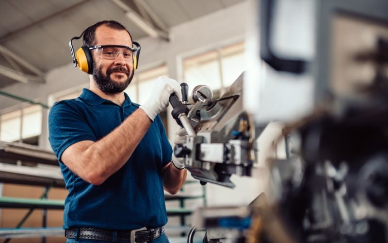 Manufacturing worker wears PPE while using machinery
