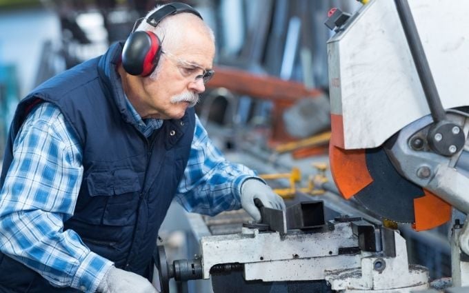 Older Worker Watches Processing of Detail on Milling Machine