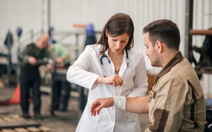 Onsite health provider examining factory worker wrist injury