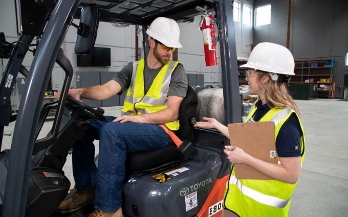 Onsite provider shows employee how to adjust forklift seat for better ergonomics