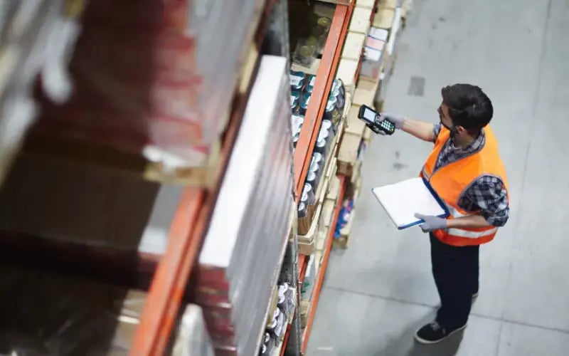 Worker with scanner making review of goods in warehouse