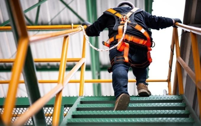 Worker wearing safety harness to protect against fall risk