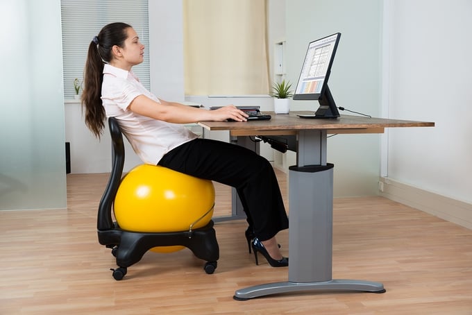 Woman slouching on a fitness ball chair at an office desk