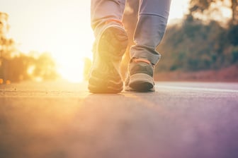 bigstock-Man-Walking-On-Road-With-Sun-L-227539483