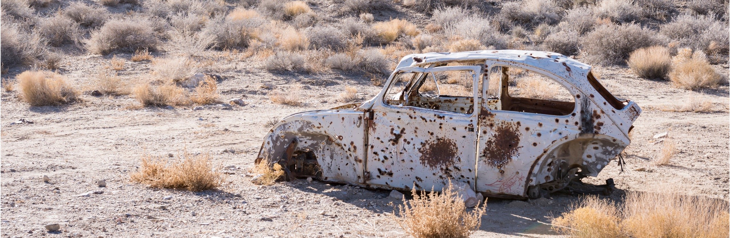 a beaten down car in the middle of nowhere