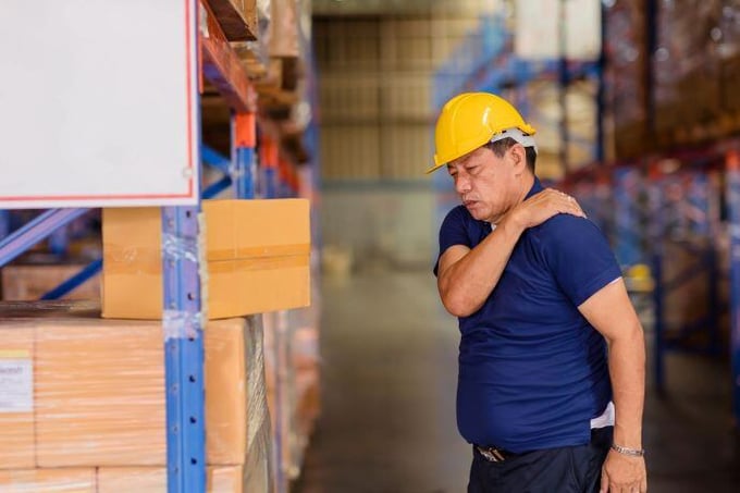 man working in a warehouse experiencing discomfort